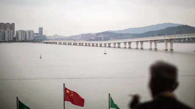 一名男子在海邊望著西灣大橋。